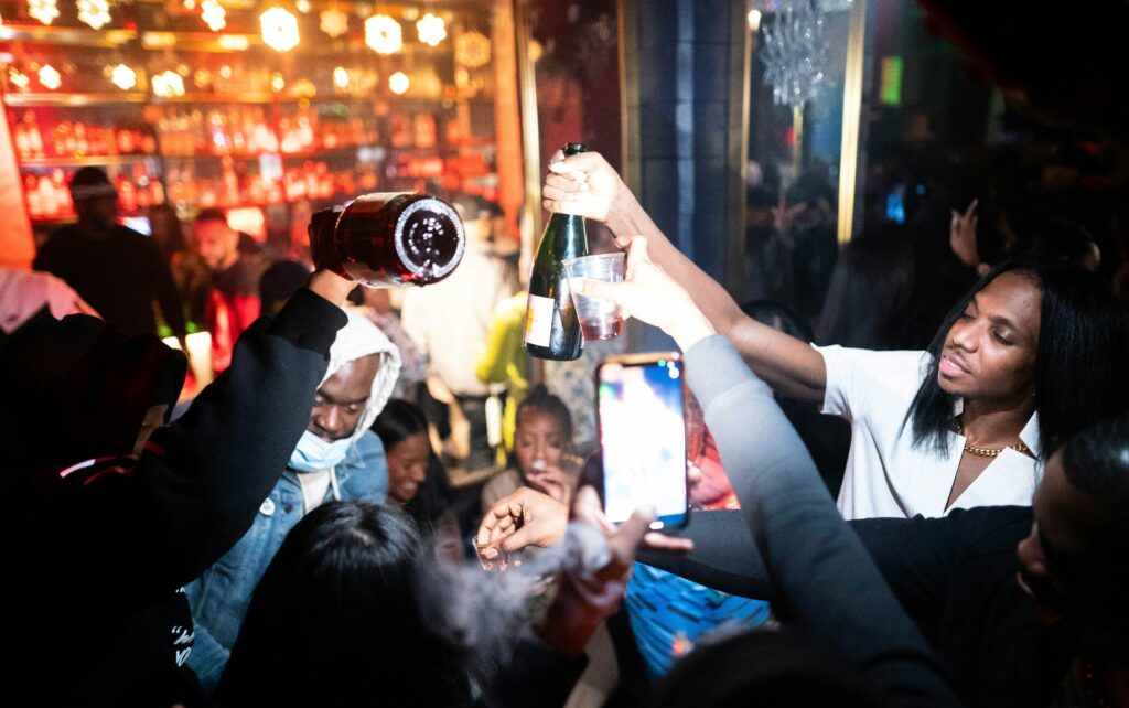 a woman holding a bottle of wine in front of a crowd of people